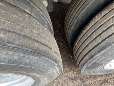 Trailer wheel set showing close-up of dual rear axles with worn tires and rims.