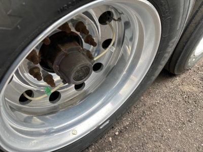 Wheel and hub of a 2024 Timpte Super Hopper trailer wheel showing lug nuts and rust spots on the hub.