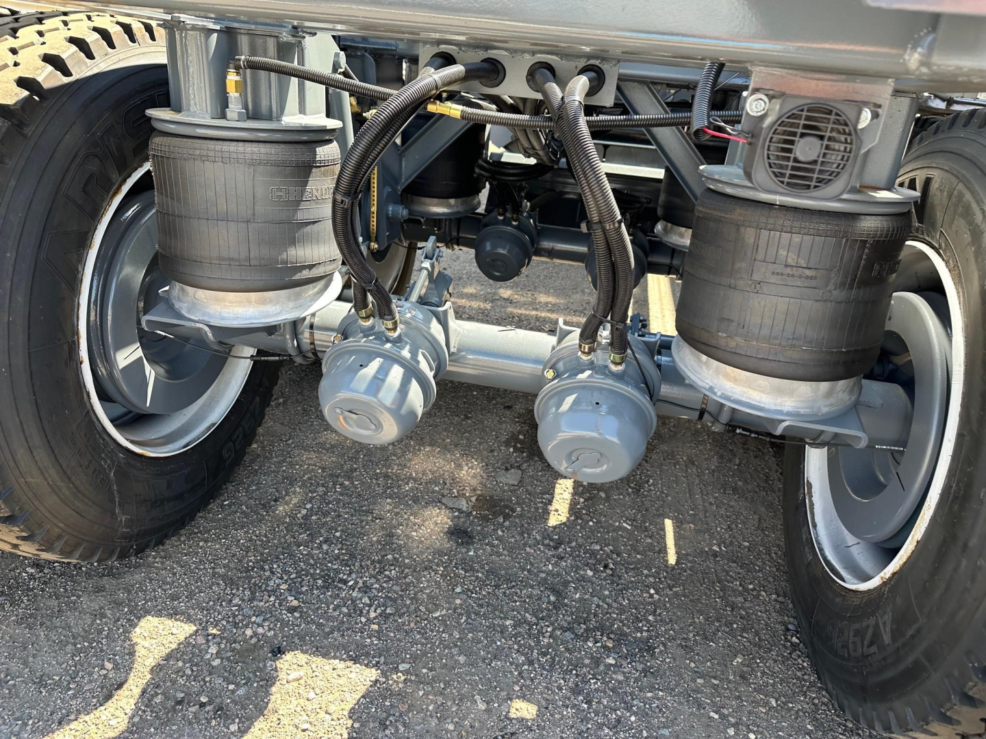 Ranco LW21-40 dump trailer undercarriage showing twin air springs, hoses, and ABS-like sensors with wheels and suspension components visible.