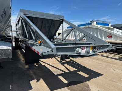 Dump trailer with a large steel hopper and truss frame showing Ranco LW21-40 structure and front hitch, yard setting with other trailers in background.