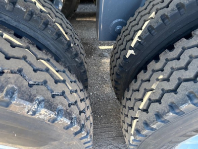 Twin rear tires of a dump trailer showing tread pattern and part of the undercarriage.