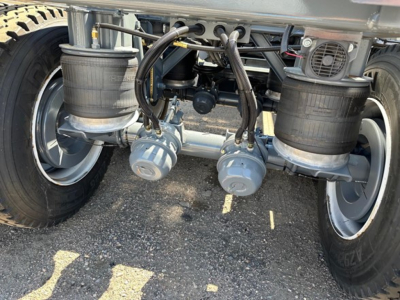 Trailer rear showing dual air tanks and hoses with gray valve manifolds under the chassis.