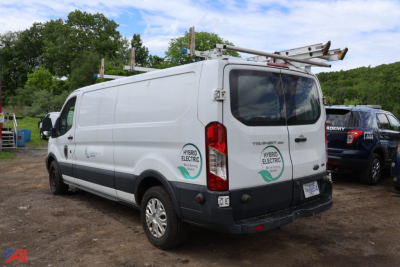 Ford Transit 350 cargo van rear side view showing ladder rack and Hybrid Electric badge on door.