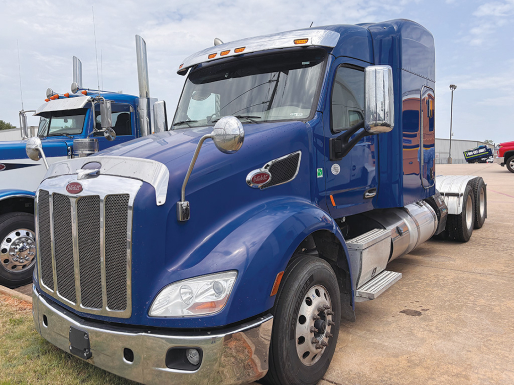 Peterbilt 579 UltraCab conventional sleeper truck in blue, front-right view showing chrome grille, large mirrors, dual fuel tanks, and badge on fender.