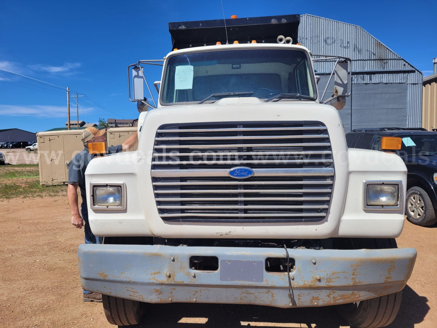 Front view of a white 1995 Ford LT9000 dump truck showing large grille, headlights, bumper, and dump bed hinges.