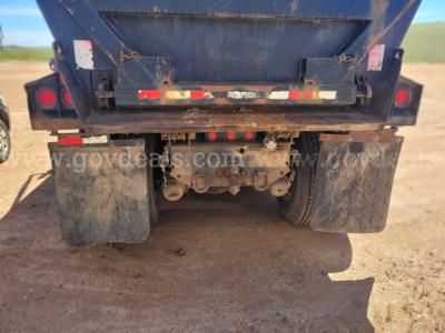 Rear view of a Ford LT9000 dump truck showing dual rear axles, mud flaps, and linkage under the dump bed.