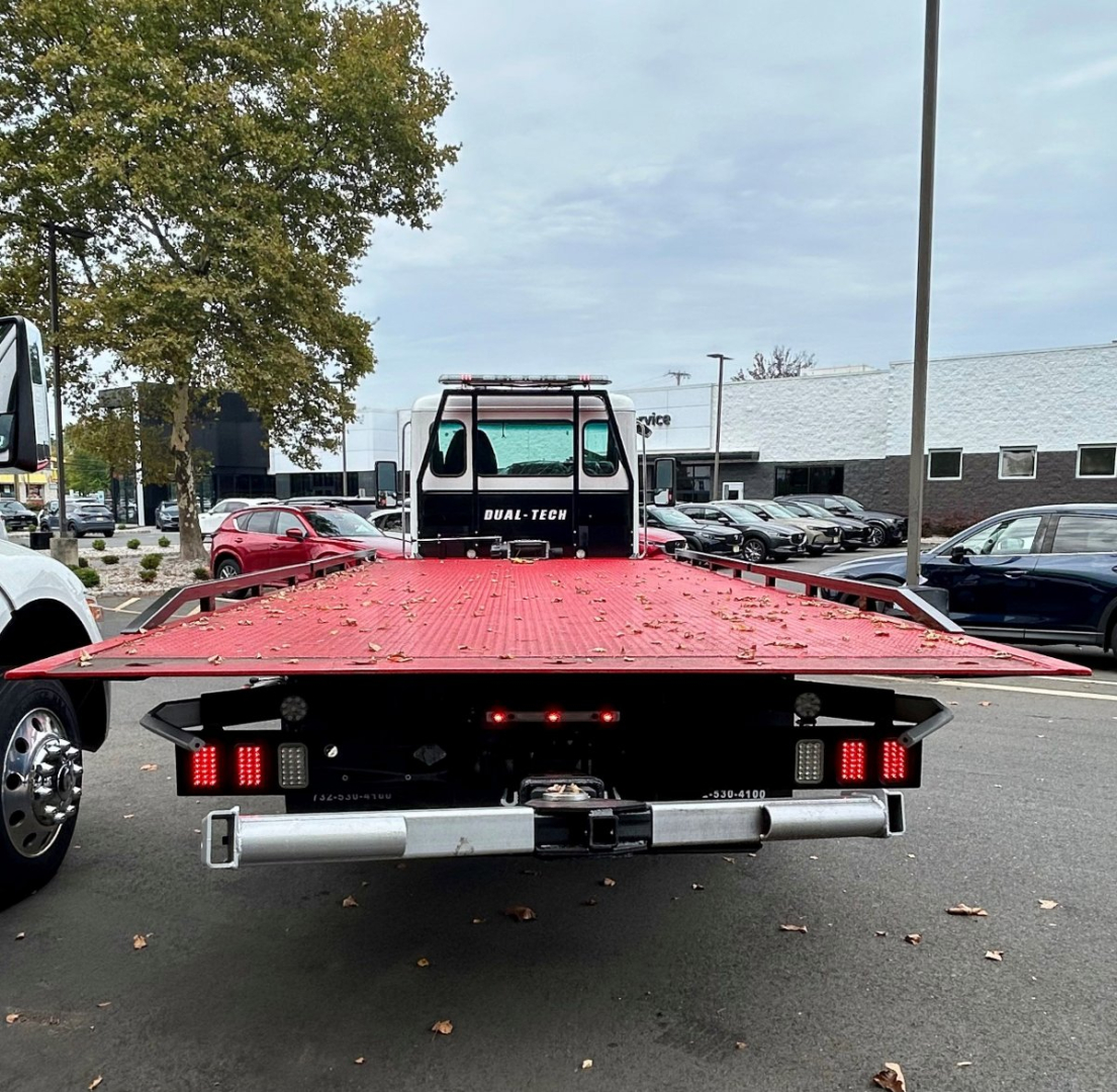 Kenworth 2025 T280 tow truck flatbed rear view showing flatbed with taillights and dual-tec branding on rear cab, high-visibility work area.