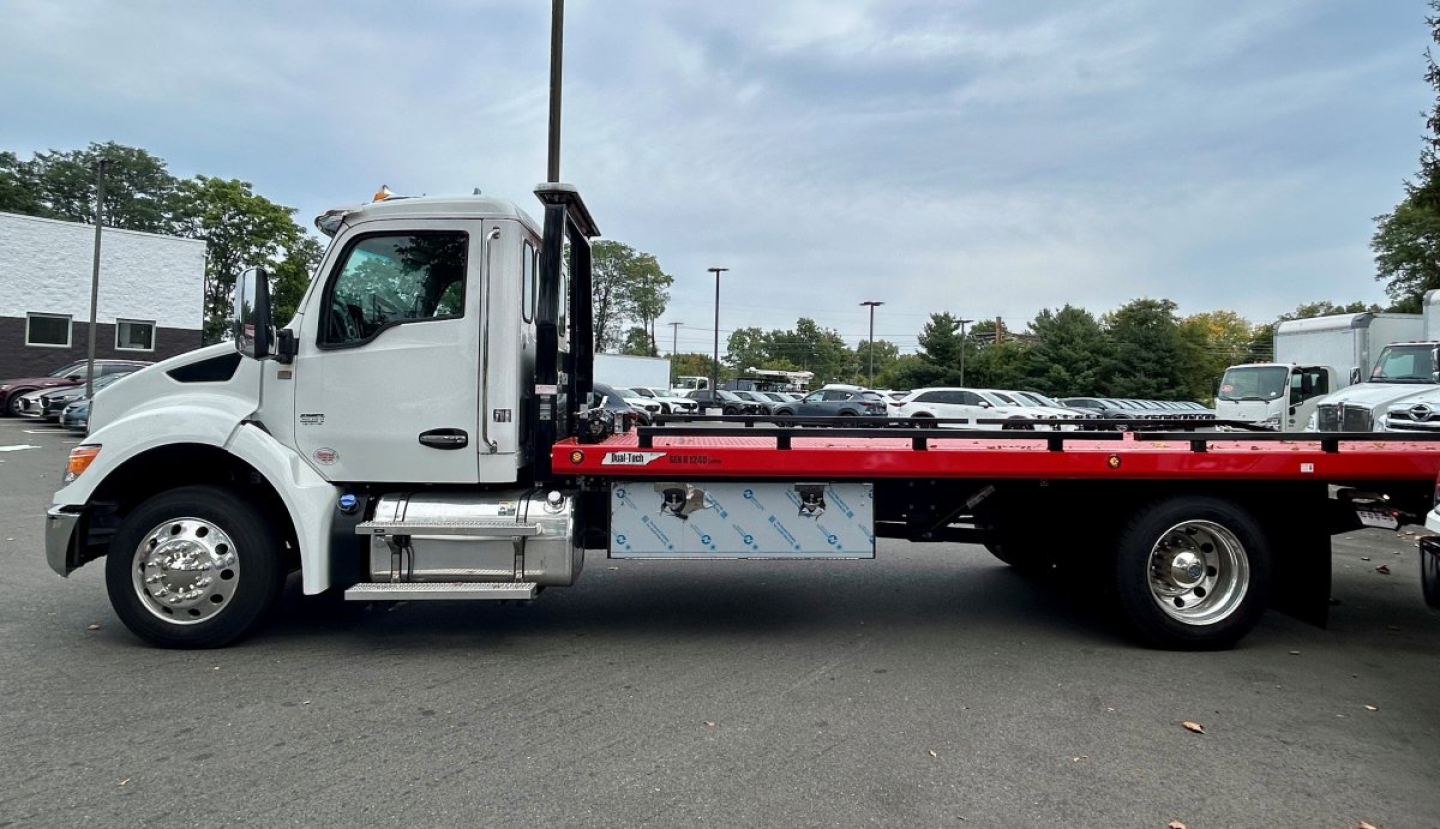 Kenworth T280 tow truck side view showing flatbed and chrome fuel tanks, cab with white paint and black accents, VIN/stock labels not visible.