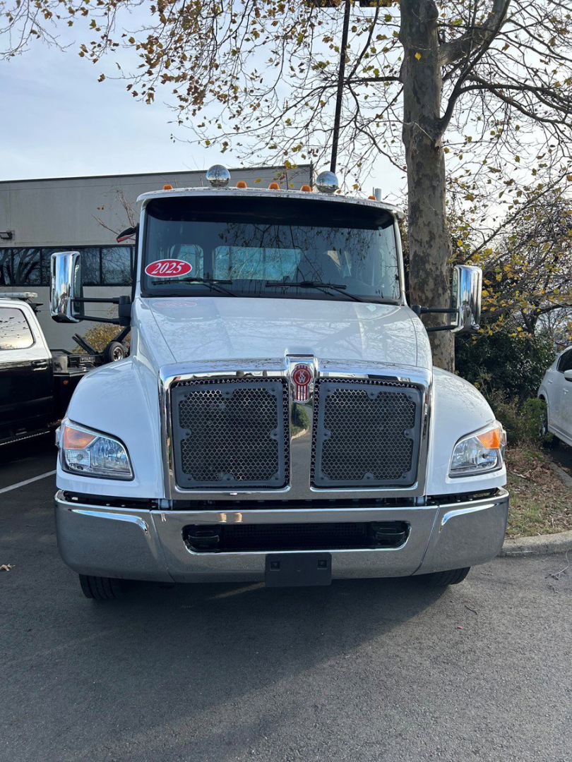 Truck front view showing 2025 Kenworth T280 tow truck grille, dual mesh grilles, chrome bumper, large side mirrors, and Kenworth emblem.