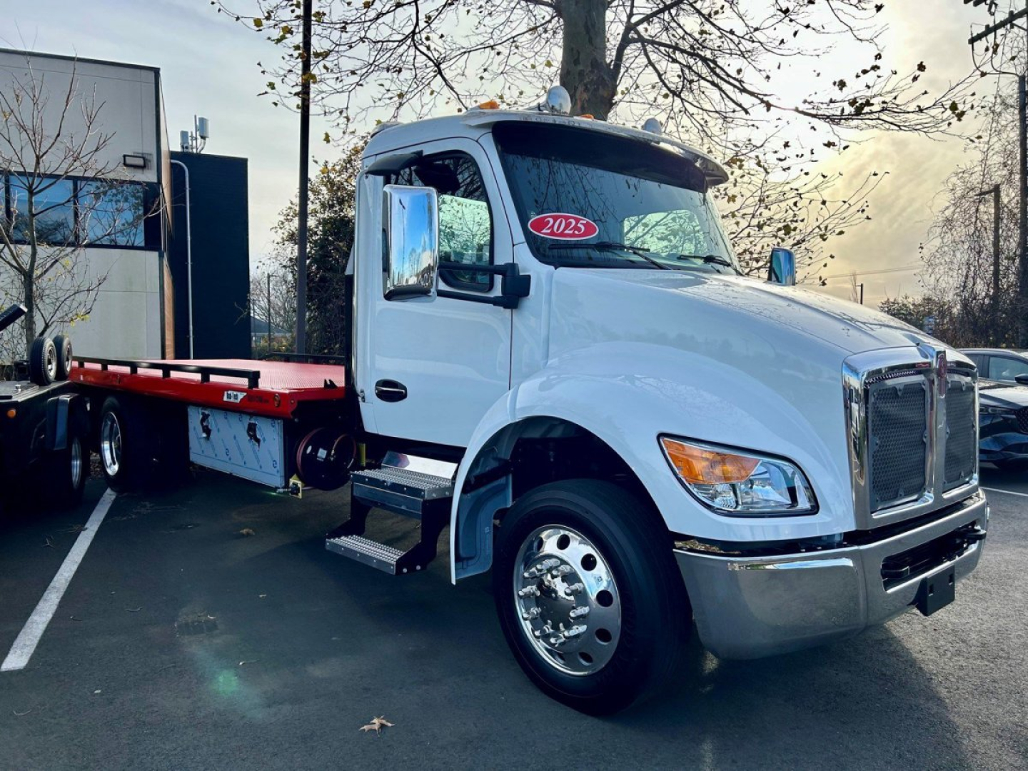 Kenworth T280 tow truck in white, front three-quarter view showing cab with 2025 sticker, side steps, and flatbed behind.
