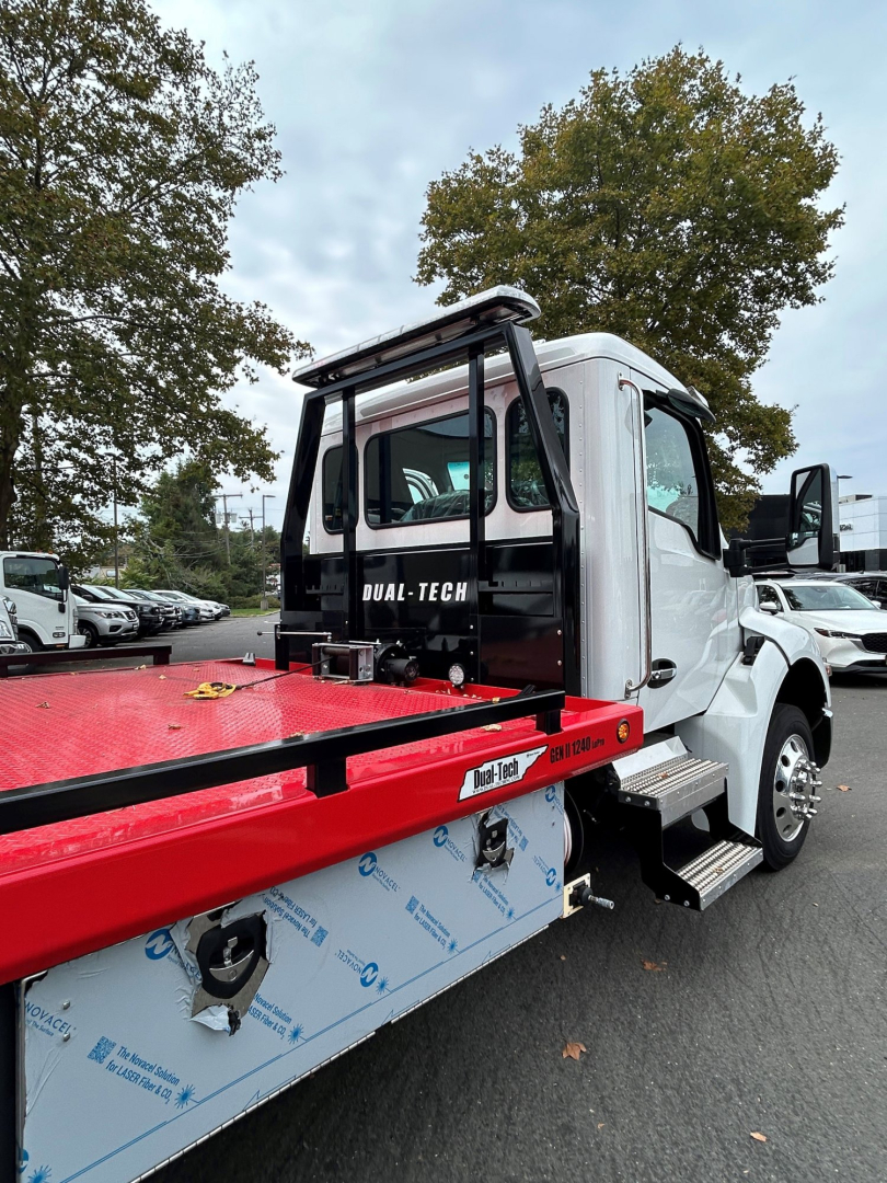 Kenworth T280 tow truck cab and flatbed with 'Duel-Tech' branding on rear window, side step, and white cab.