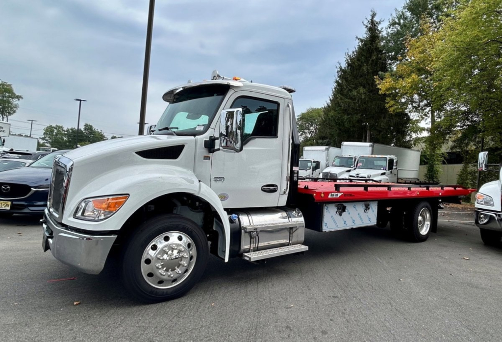 Kenworth T280 tow truck in white, side view showing long flatbed with chrome fuel tanks and dual rear wheels.