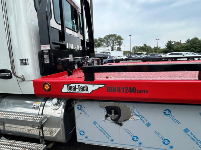 Kenworth T280 tow truck side view showing Dual-Tech GEN II 1240 Lopro red equipment carrier mounting with white cab and metal steps; visible VIN sticker area and stock number label.
