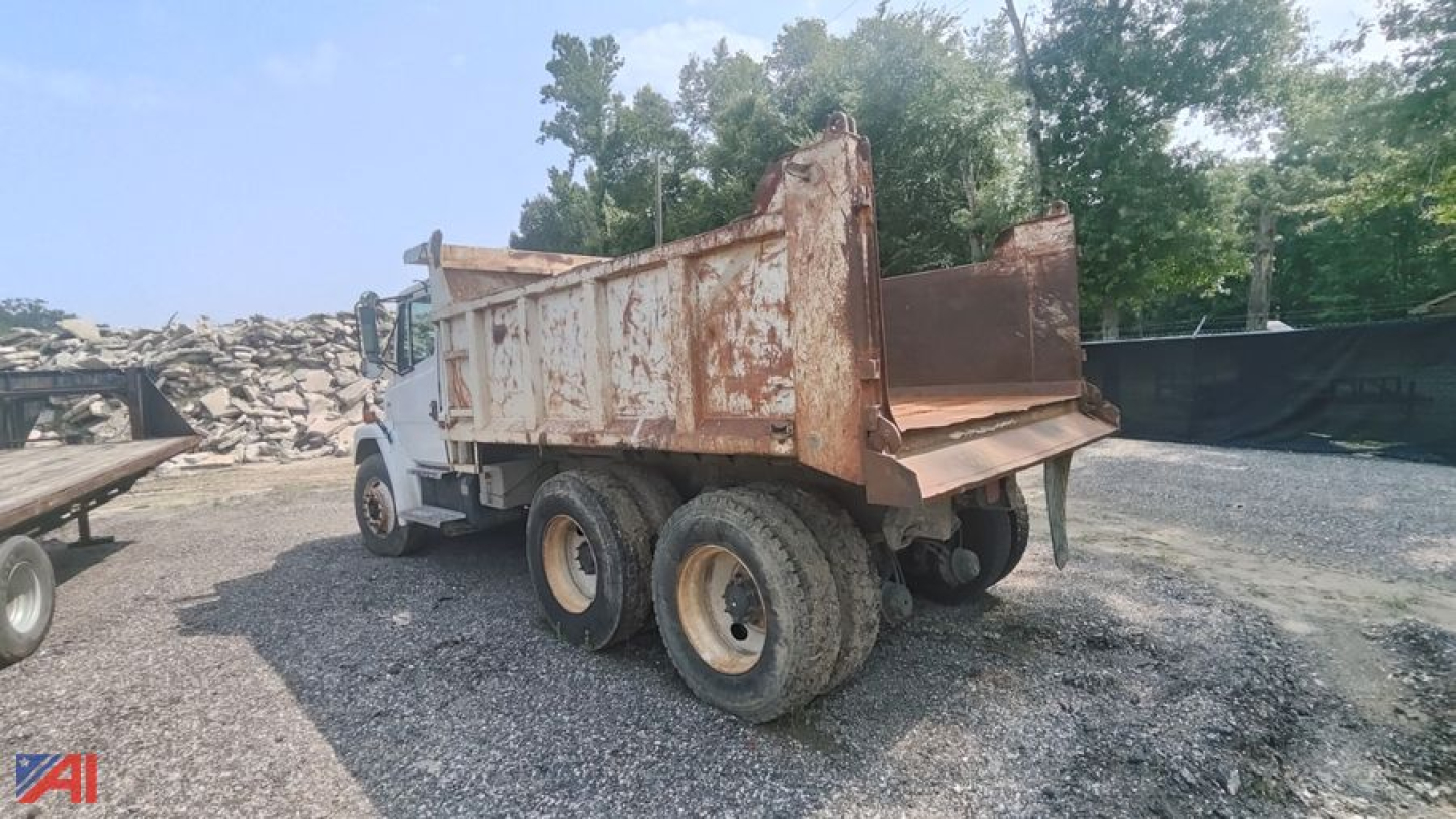 Dump truck bed and rear view of a 2004 Freightliner FL80 dump truck in a gravel lot.