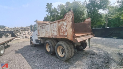 Dump truck bed and rear view of a 2004 Freightliner FL80 dump truck in a gravel lot.