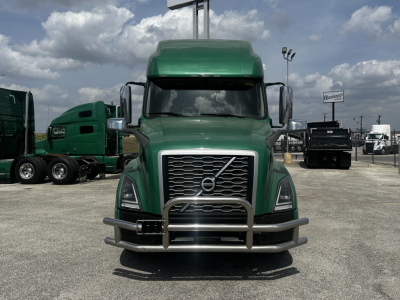 Green Volvo VNL64T760 truck front view with chrome grille, bumper, and large side mirrors.