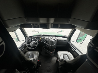 Volvo VNL64T760 truck cab interior showing steering wheel and dashboard, front seats, and windshield from cabin view.