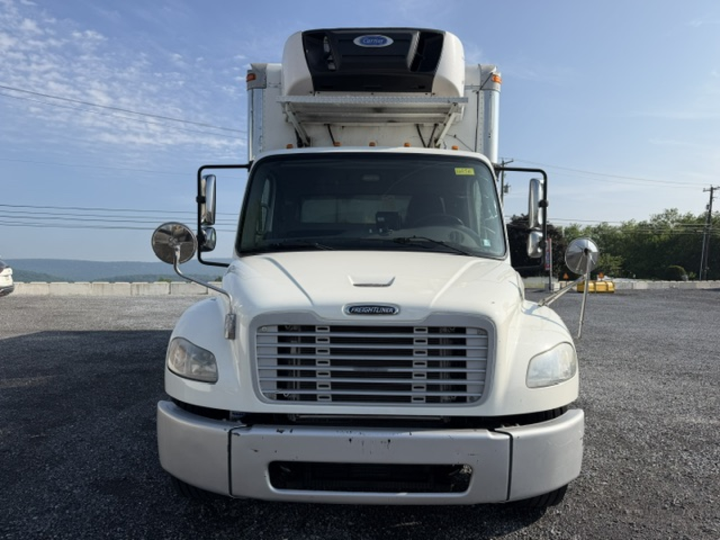 Freightliner M2-106 refrigerated truck front view showing grille, bumper, and mounted refrigerated unit on the cab with side mirrors.