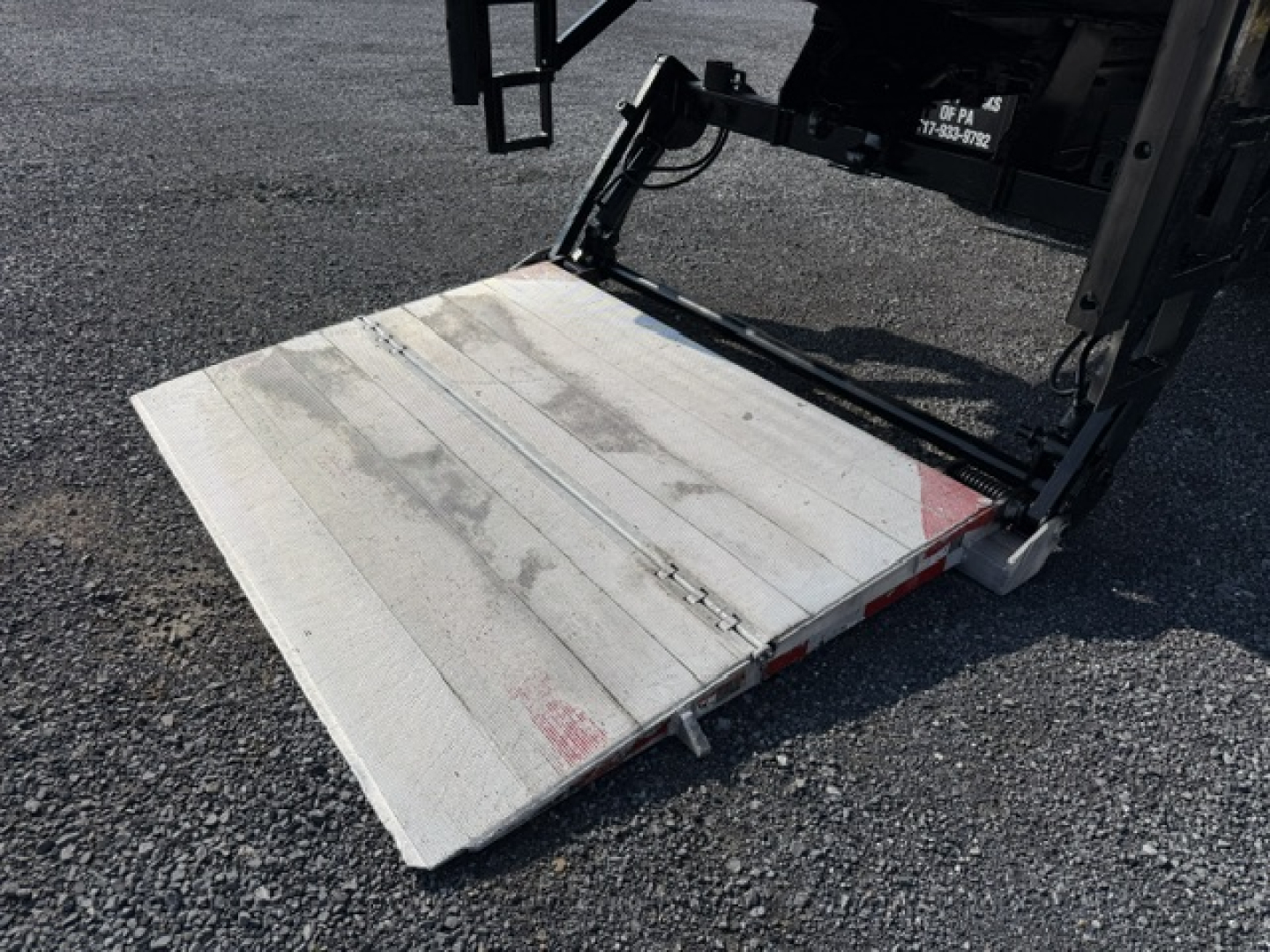 Truck rear with lowered aluminum liftgate showing metal platform and hydraulic assembly for a 2016 Freightliner M2-106 refrigerated truck.