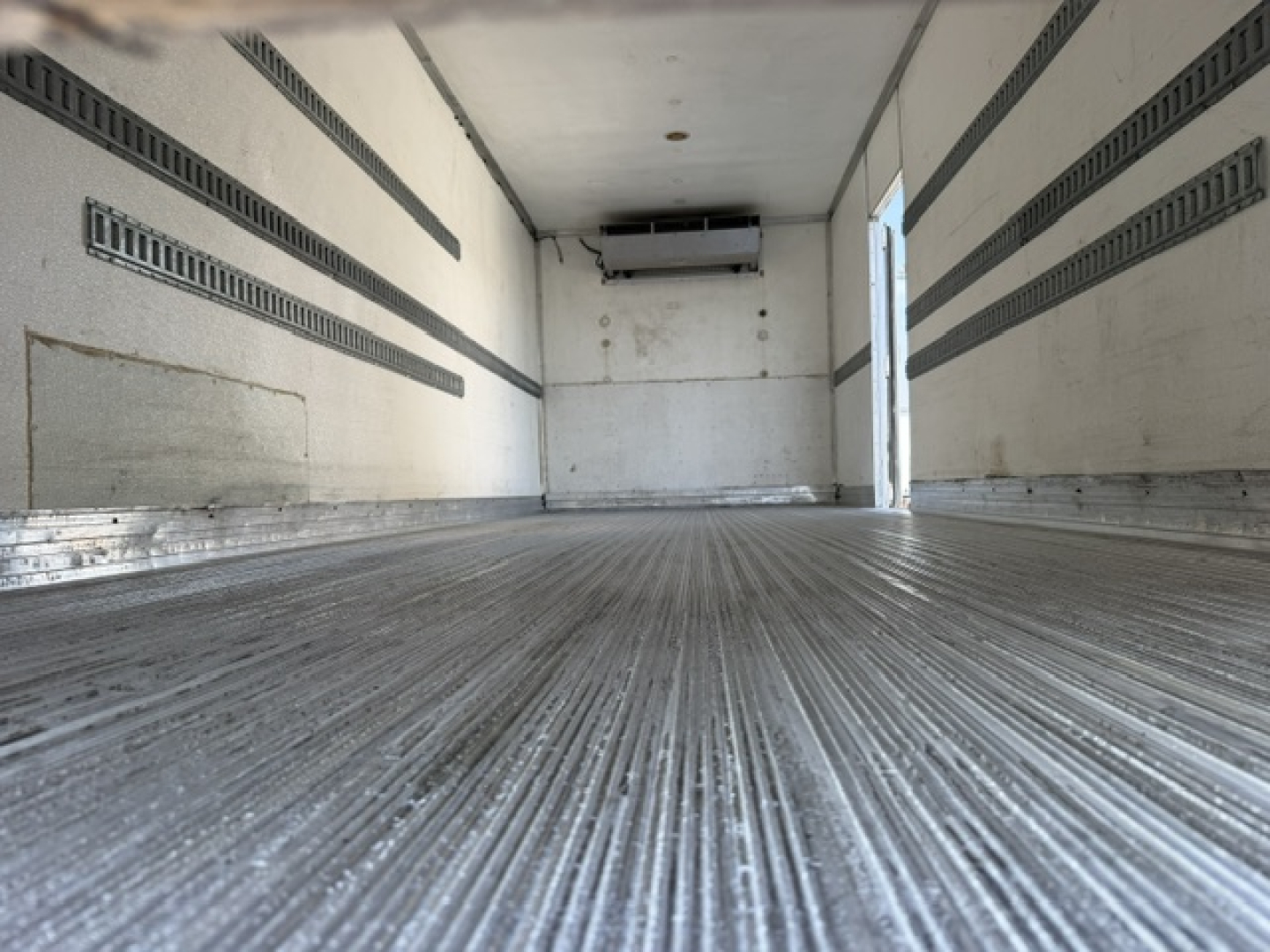 Truck trailer interior showing clean metal floor and insulated walls with ETR side rails; back door open, refrigerated trailer interior