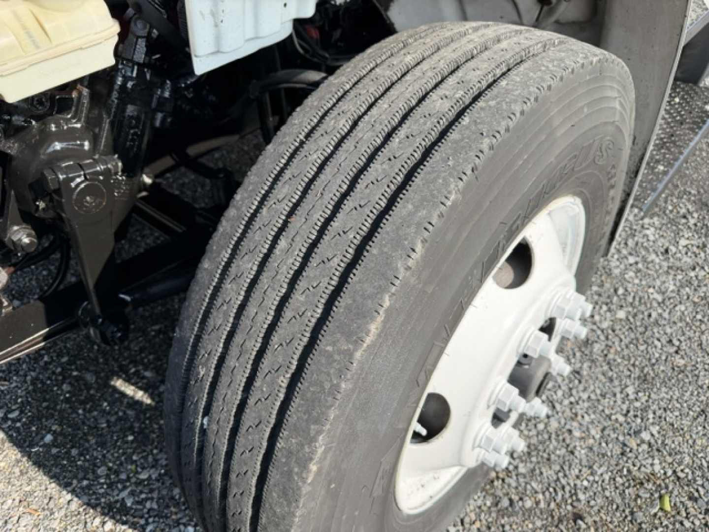 Front right wheel of a 2016 Freightliner M2-106 refrigerated truck showing dual rear tires and wheel hub; part of chassis and underbody components visible.