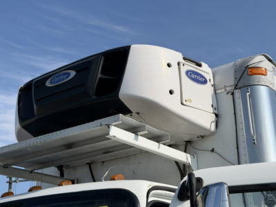 Carrier refrigeration unit mounted on Freightliner M2-106 truck cab in a refrigerated vehicle setup.