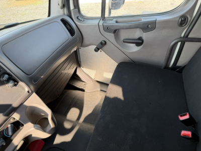 Freightliner M2-106 cab interior showing passenger seat with seatbelt buckles and dashboard area.