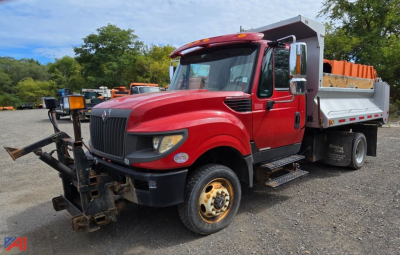 Dump truck with plow and red cab, International TerraStar, side view showing snow plow mount and dump bed in an outdoor lot.