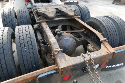Rear chassis of a Mack CXN613 truck showing rusty steel frame, dual rear axles, hitch, chains, and wheel tires visible.