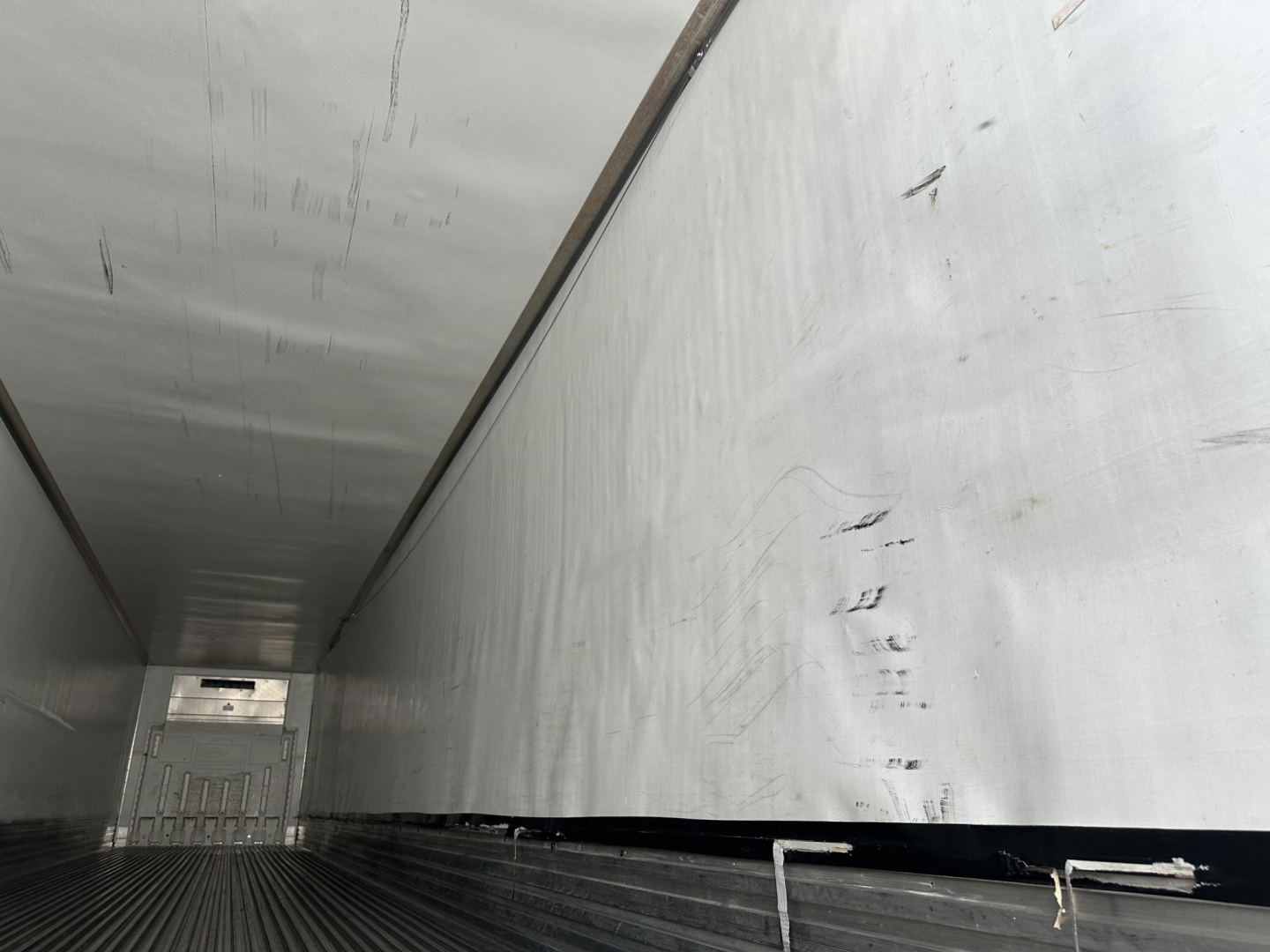 Trailer interior showing aluminum walls and ribbed floor of a 2018 Utility 3000R trailer with a rear door.