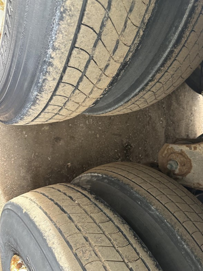 Double set of trailer tires with tread pattern and a portion of undercarriage visible.