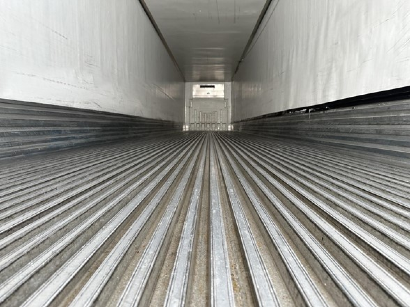 Trailer interior showing ribbed floor and sidewalls of a Utility 3000R reefer trailer, empty cargo area with rear door visible at far end.