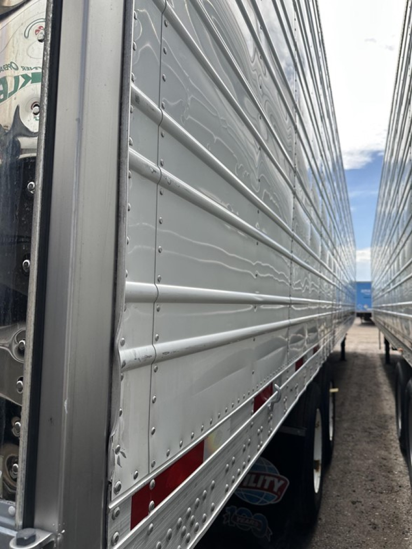 Trailer side view showing aluminum riveted panels of a 2018 Utility 3000R reefer trailer with ribbed siding and visibility of wheels and rear compartments.