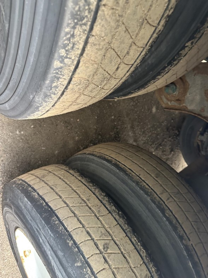Trailer wheels and tires in view showing tread wear and rim; undercarriage components visible.