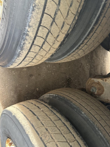 Double set of trailer tires with tread pattern and a portion of undercarriage visible.