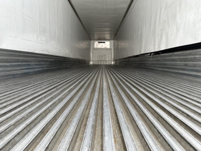 Trailer interior showing ribbed floor and sidewalls of a Utility 3000R reefer trailer, empty cargo area with rear door visible at far end.