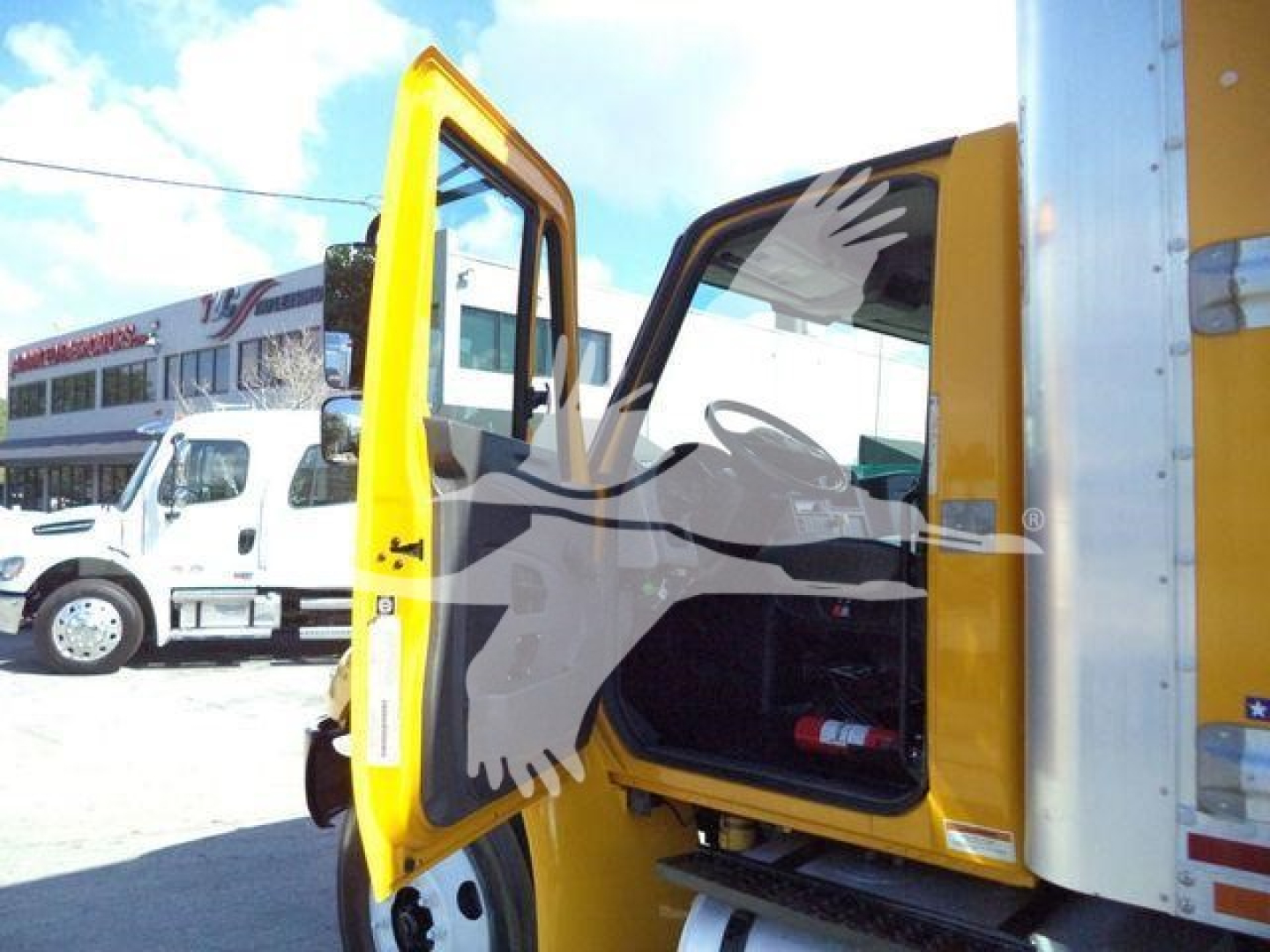 Truck cab door open showing interior of a 2019 International Durastar box truck, yellow cab with black steps and side door open.