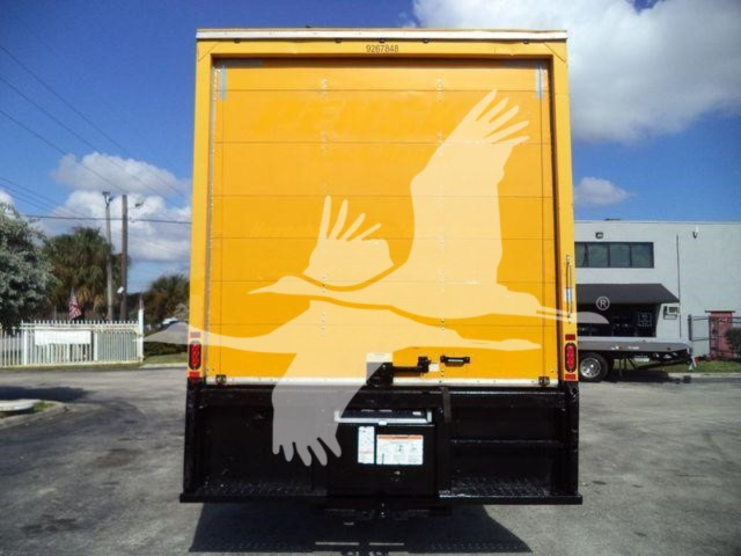 Rear view of a 2019 International Durastar box truck, yellow back doors with a white bird graphic, black bumper and license plate area.