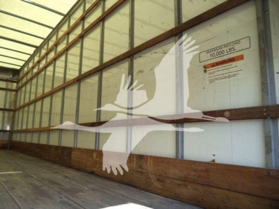 Image shows the interior of a box truck trailer with side panels and a warning label. A large white silhouette of a bird watermark overlays the scene.