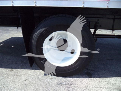 Truck wheel and tire under a box truck, white steel rim, visible portion of chassis and undercarriage.