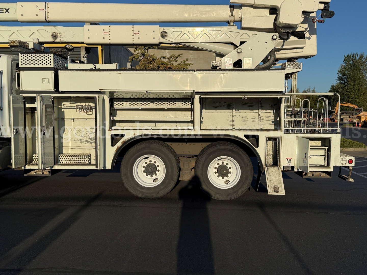 Truck side view showing a bucket boom on a 2010 International 7500 with multiple compartments and stabilizers.