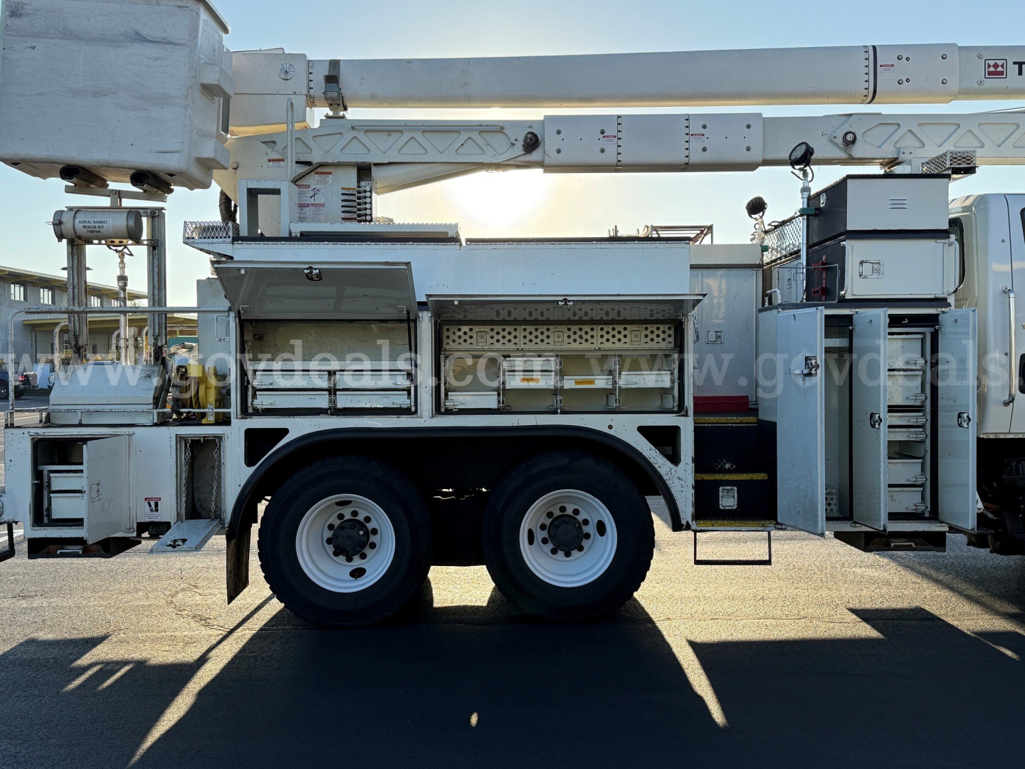 International 7500 bucket truck side view showing utility compartments and dual rear axles with ladders and work platform.