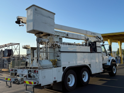 International 7500 bucket truck with aerial lift mounted on chassis, white utility body, bucket stowed, rear platform visible, side mirrors and stabilizers.