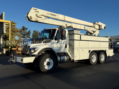 International bucket truck with Terex boom labeled TEREX on the crane arm, dual rear axles, utility body with compartments, front cab and headlights visible.