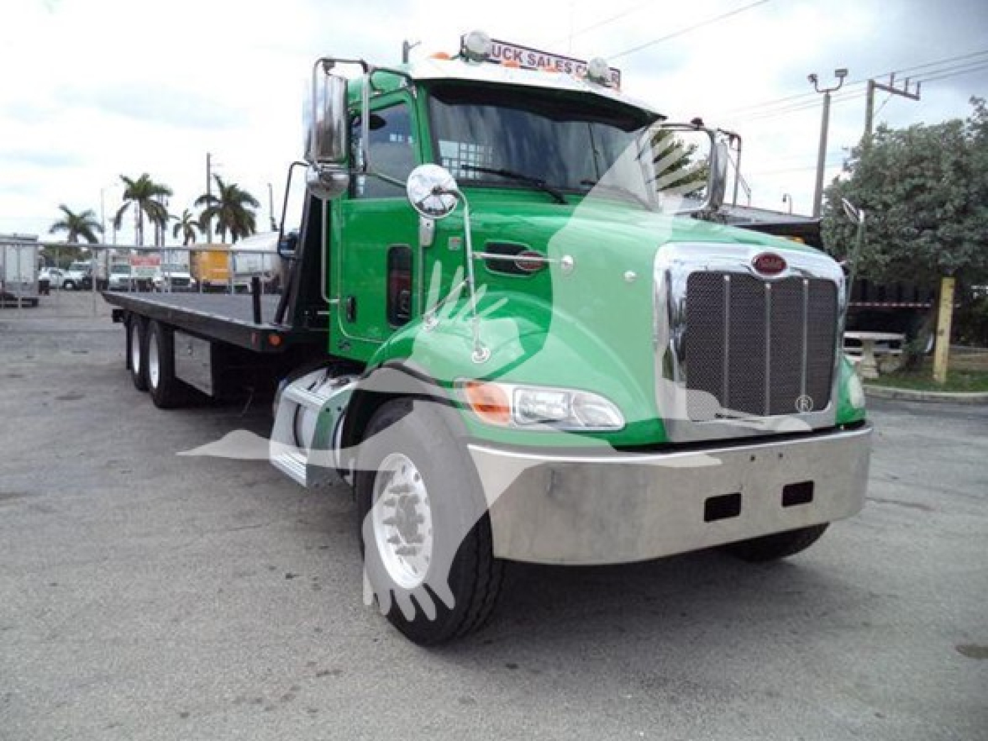 Peterbilt 348 tow truck in green and chrome with a flatbed, front grille, and large bumper.