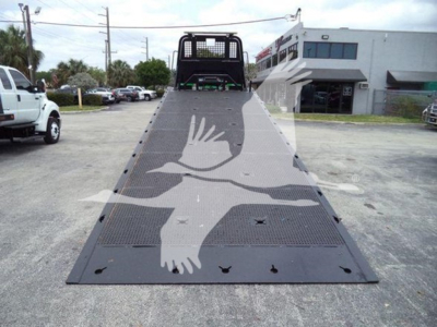 Tilted view of a 2016 Peterbilt 348 rollback truck with a metal ramp deck and rear winch area in an outdoor lot.