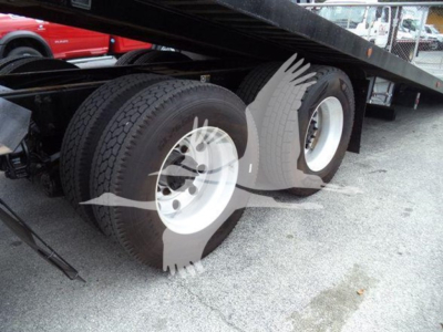 Peterbilt 348 rollback truck rear dual tires and undercarriage with white rims and black trailer frame.