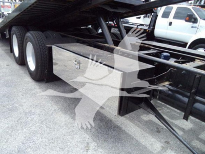Peterbilt 348 rollback truck undercarriage showing a diamond-plate toolbox mounted under the frame with twin rear axles and metal framework.