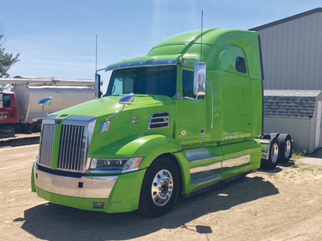 Green 2021 Western Star 5700XE sleeper cab truck in a lot showing side and front profile.