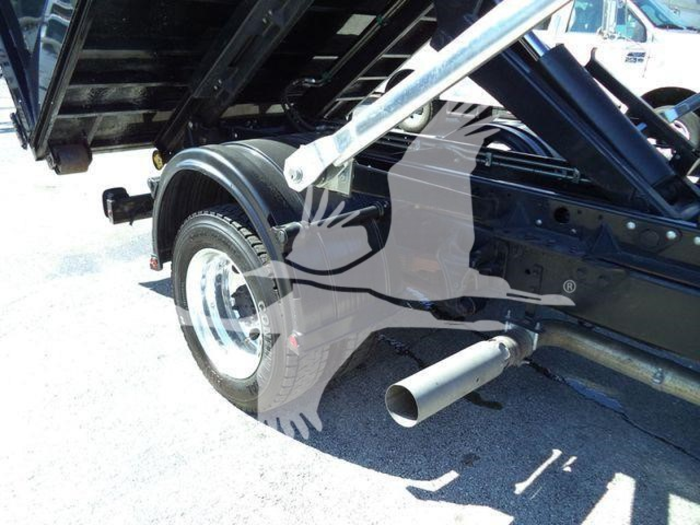 Truck frame with rear wheel and exhaust pipe visible in a Silverado 6500HD rolloff truck undercarriage